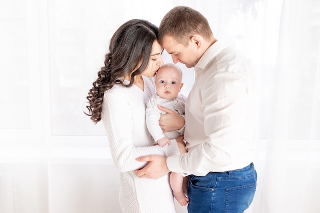 Glückliche Familie Mutter und Vater halten ein neugeborenes Baby zu Hause, das Konzept der glücklich liebenden Familie, Lebensstil