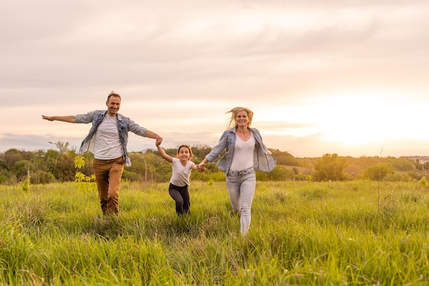 Glückliche Familie: Mutter, Vater, Kindertochter in der Natur bei Sonnenuntergang.