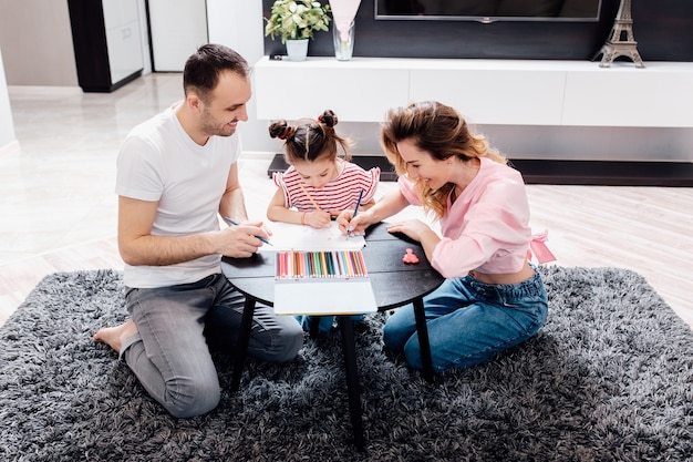 Glückliche Familie Mutter Vater und Kinder zeichnen zu Hause zusammen.