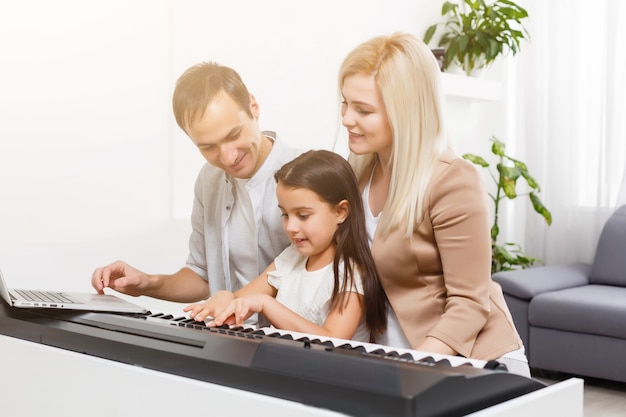 Glückliche Familie, Mutter, Vater und Tochter, die zu Hause Klavier spielen, Konzept für die Familienbeziehung. Musikschule und Musikfamilie.