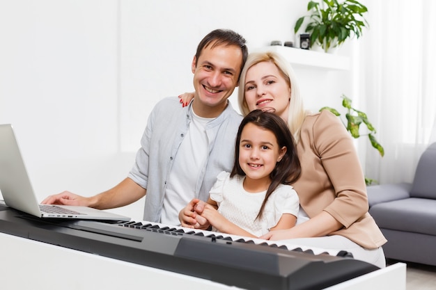 Glückliche familie, mutter, vater und tochter, die zu hause klavier spielen, konzept für die familienbeziehung. musikschule und musikfamilie.
