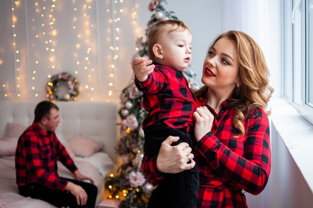 Glückliche Familie nahe Weihnachtsbaum im gemütlichen Innenraum