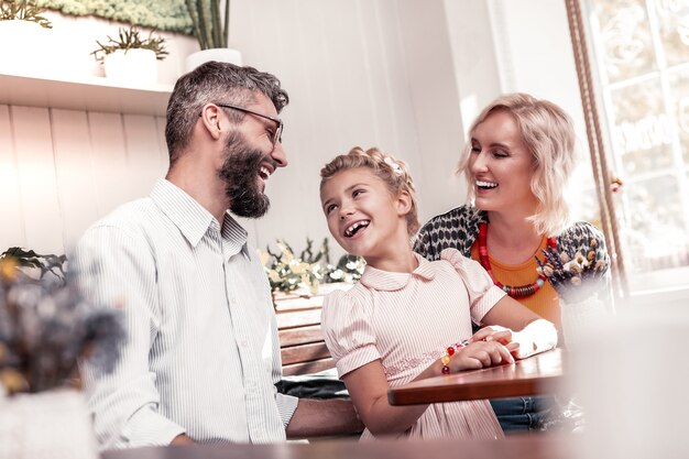 Glückliche Familie. Nettes angenehmes Mädchen, das ihren Vater beim Sitzen am Tisch im Café ansieht