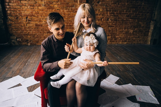 Glückliche Familie, posiert auf einem Stuhl in einem Innenraum des Studios, eine starke eng verbundene Familie