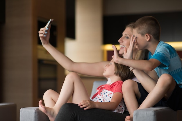 Glückliche Familie sitzt auf dem Sofa und nutzt das Handy für Videoanrufe zu Hause