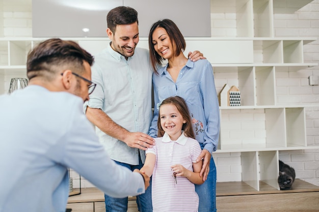 Glückliche Familie spricht mit einem Immobilienmakler über einen Schlüssel ihres neuen Zuhauses.