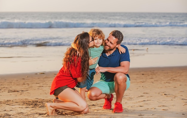 Glückliche Familie und Kind, die den Sonnenuntergang in der Sommerfreizeit am Strand genießen