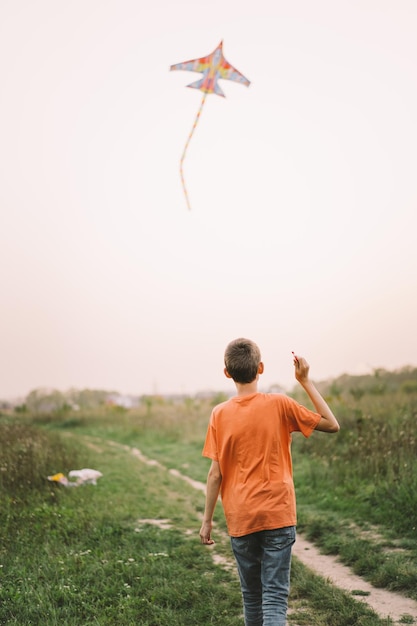 Glückliche Familie und Kinder laufen auf der Wiese mit einem Drachen im Sommer in der Natur Familie spielt mit Drachen, während sie entlang des ländlichen Sommerfeldes läuft Familientag