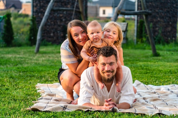 Glückliche Familie und kleine Kinder auf einer Decke im Gras im Sommer