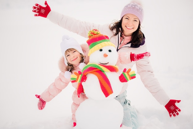 Glückliche Familie und Schneemann im Winterpark