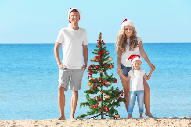 Glückliche Familie und Weihnachtsbaum am Strand