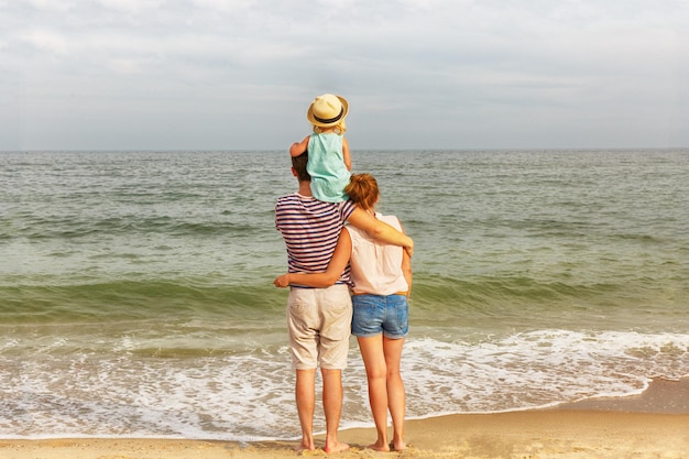 Glückliche Familie Vater, Mutter und Tochter stehen an der Küste Rückansicht