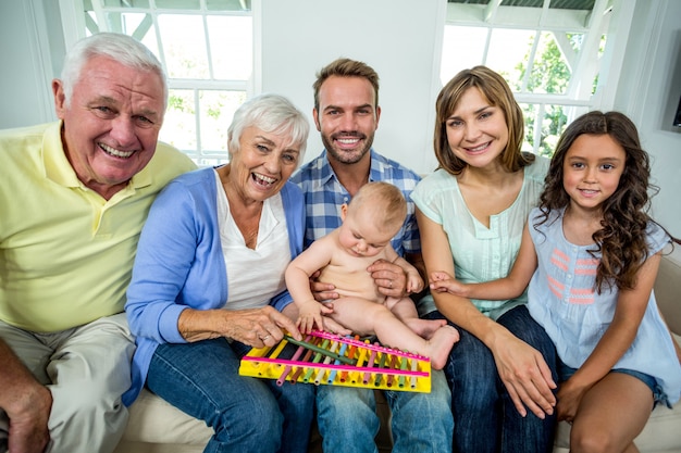 Glückliche Familie von mehreren Generationen, die zu Hause auf Sofa sitzt