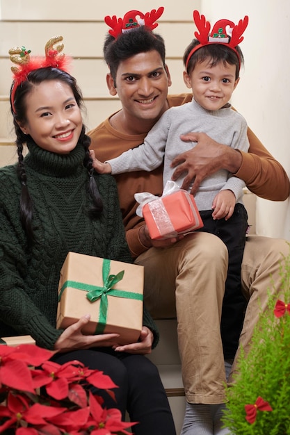 Glückliche Familie von Mutter, Vater und kleinem Sohn, die zu Hause zusammen Weihnachten feiern