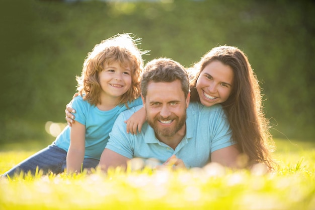 glückliche familie von mutter, vater und sohn kind entspannen sich im grünen gras des sommerparks, familienbindung.