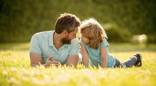 Glückliche Familie von Papa und Sohn entspannen sich im Sommerpark bei der Adoption von grünem Gras