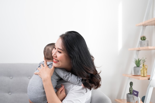 Glückliche Familie zu Hause. Mutter mit Babytochter im Wohnzimmer am gemütlichen Wochenendmorgen holding