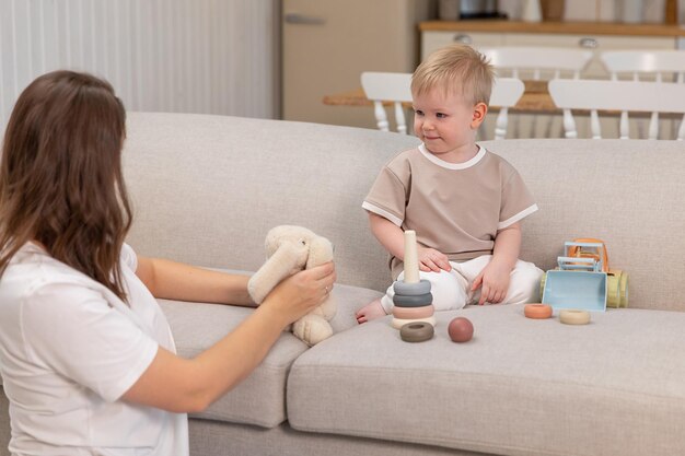 Glückliche Familie zu Hause Mutter und Baby Junge spielen mit Spielzeug in der Couch zu Hause in Innenräumen Kleinkind