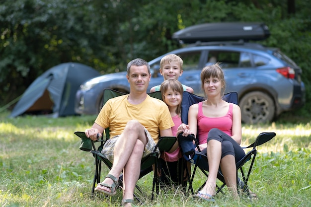 Glückliche Familieneltern und Kinder, die zusammen am Campingplatz ausruhen.