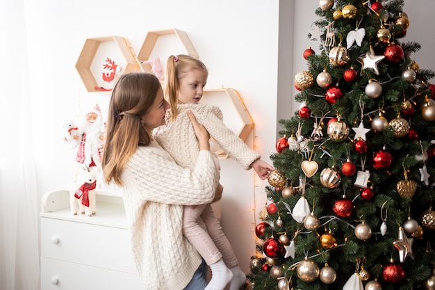 Glückliche Familienfamilienmutter und -kind zu Hause nahe Weihnachtsbaum