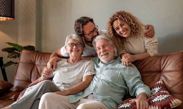 Glückliche Familiengruppe mit mehreren Generationen, die zu Hause auf dem Sofa sitzt und Zeit miteinander verbringt