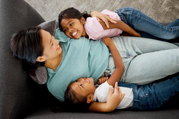 Glückliche Familienkinder und Mutter, die sich mit ihrer Tochter auf einem Sofa verbinden, entspannen und glücklich in einem Wohnzimmer von oben Lieben Sie Kinder und Mutter, die lachen und lieben, Zeit zusammen genießen und Eltern sein