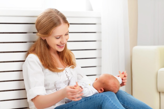 Glückliche Familienmutter spielt und lacht mit ihrem neugeborenen Baby