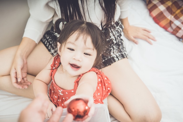 Glückliche Familienmutter und -baby, die nach Hause an den Weihnachtsfeiertagen spielt.