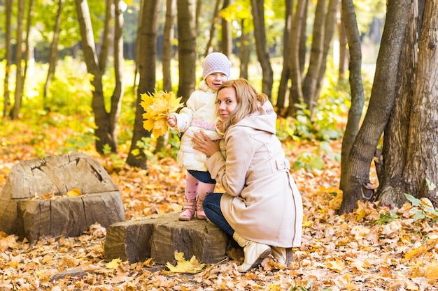 Glückliche Familienmutter und Baby lachen mit Blättern im Naturherbst