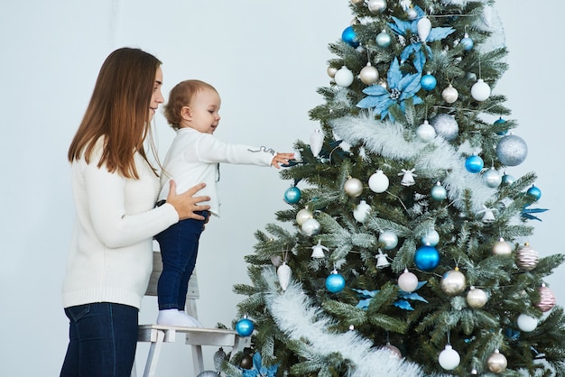 Glückliche Familienmutter und -baby verzieren Weihnachtsbaum