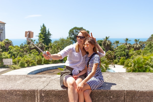 Glückliche Familienmutter und ihre entzückende kleine Tochter im Sommerurlaub, die Selfie mit Smartphone machen taking