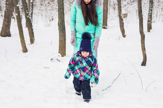 Glückliche Familienmutter und Kinderbabytochter auf einem Winterspaziergang im Wald.