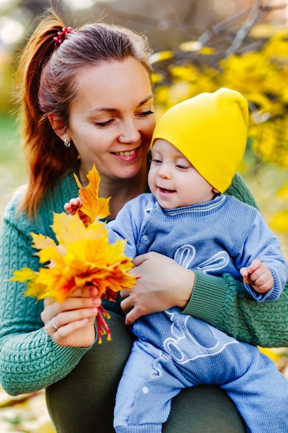 Glückliche Familienmutter und Kindertochter, die auf Herbstspaziergang spielen und lachen