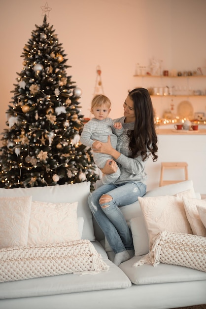 Glückliche Familienmutter und Kindertochter nahe Weihnachtsbaum zu Hause