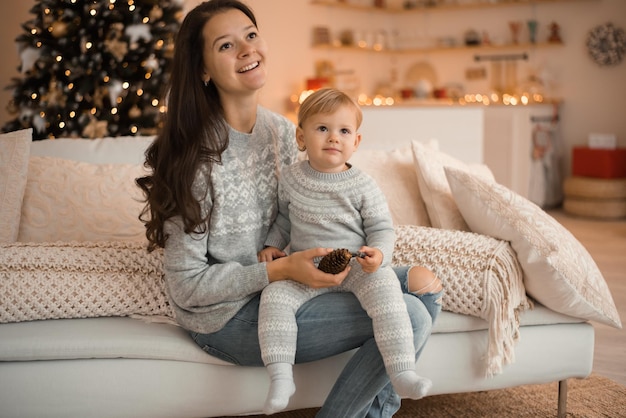 Glückliche Familienmutter und Kindertochter nahe Weihnachtsbaum zu Hause