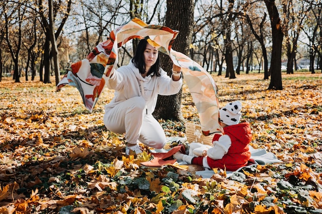 Glückliche Familienmutter und kleine Kleinkind-Tochter haben gemeinsam Spaß beim Herbstpicknick