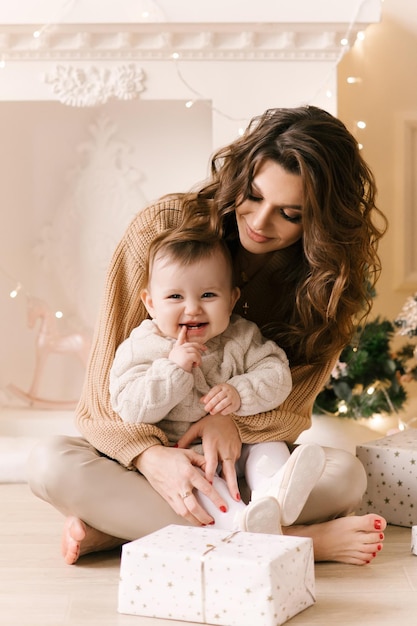 Glückliche Familienmutter und Tochter am Weihnachtsmorgen am Weihnachtsbaum mit Geschenken