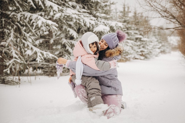 Glückliche Familienmutter und Tochter haben Spaß beim Spielen im Winter im Freien. Familie im Winterwald