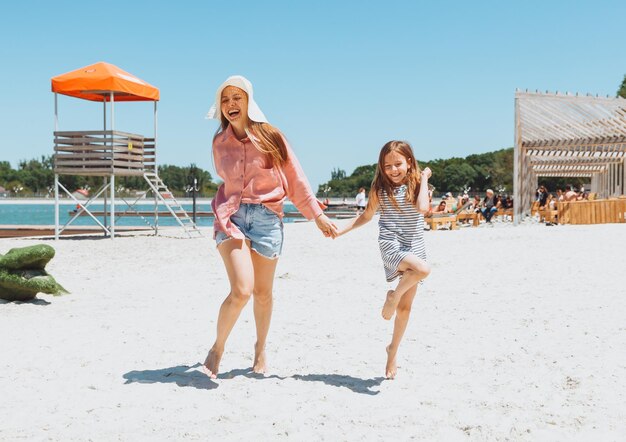 Glückliche Familienmutter und -tochter laufen, lachen und spielen am Strand Mutter und zwei Mädchen am Strand