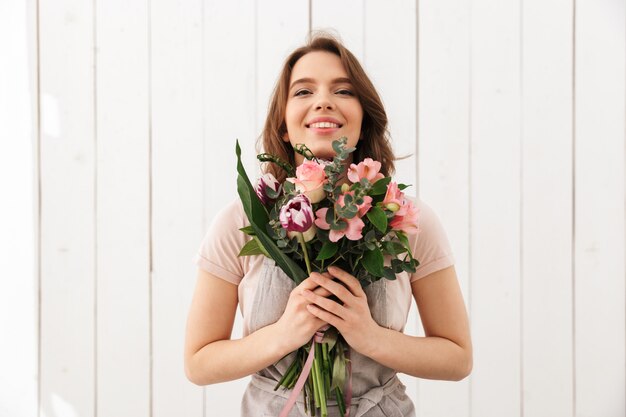 Glückliche Floristenfrau, die mit Blumen steht