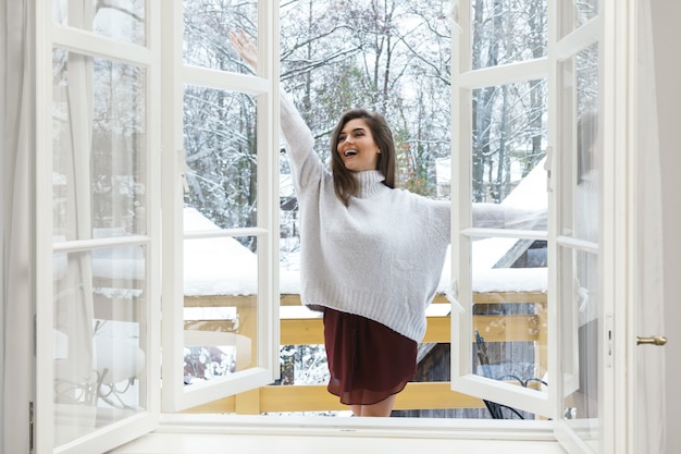 Glückliche Frau auf dem Balkon am verschneiten Wintertag