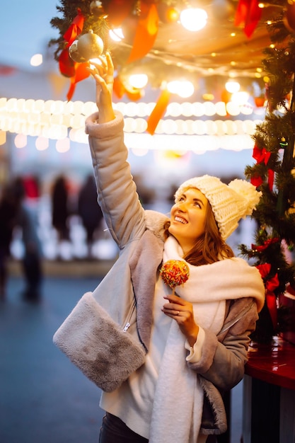 Glückliche Frau auf dem Weihnachtsmarkt mit karamellisiertem Apfel Outdoor-Aktivitäten zu Weihnachten