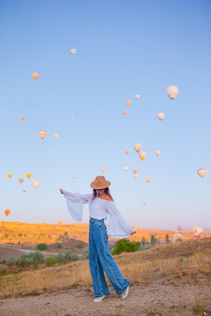 Glückliche Frau bei Sonnenaufgang, die Heißluftballons in Kappadokien, Türkei, beobachtet