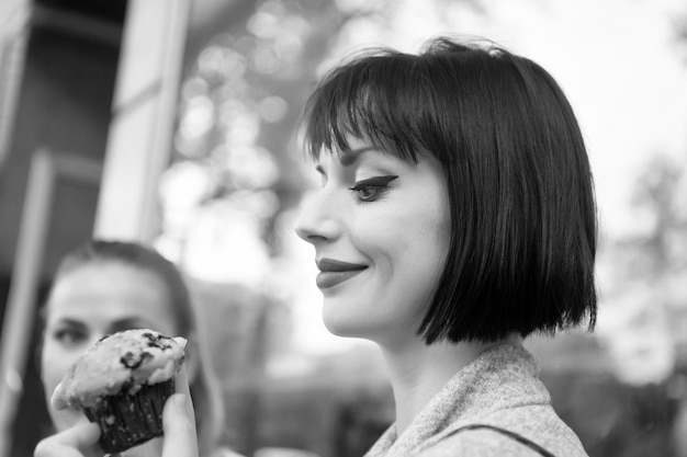 Glückliche Frau Blick auf Cupcake in Paris Frankreich Essen Sinnliche Frau mit Muffin-Kuchen-Snack Dessert-Snack Schönheits-Look Make-up Hunger Versuchung Appetit