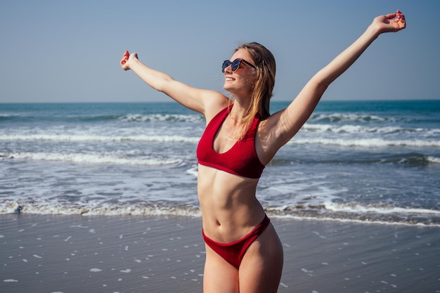 Glückliche Frau, die am Strand lächelt und Spaß hat Sommerporträt eines jungen schönen Mädchens im roten Bikini