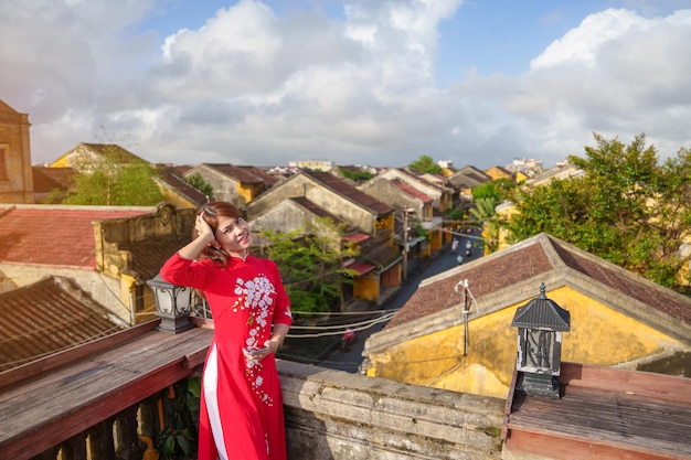Glückliche Frau, die Ao Dai vietnamesisches Kleid trägt, Sightseeing-Ansicht auf dem Dach der antiken Stadt Hoi An in Vietnam, Wahrzeichen und beliebt für Touristenattraktionen Vietnam und Südost-Reisekonzept