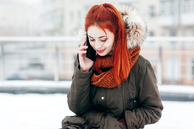 Glückliche Frau, die auf dem Handy in der Straße im Winter anruft