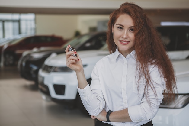 Glückliche Frau, die Autoschlüssel zu ihrem neuen Automobil hält