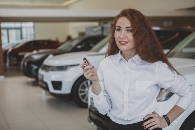 Glückliche Frau, die Autoschlüssel zu ihrem neuen Automobil hält