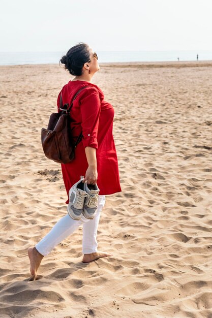 Glückliche Frau, die barfuß am Strand spazieren geht